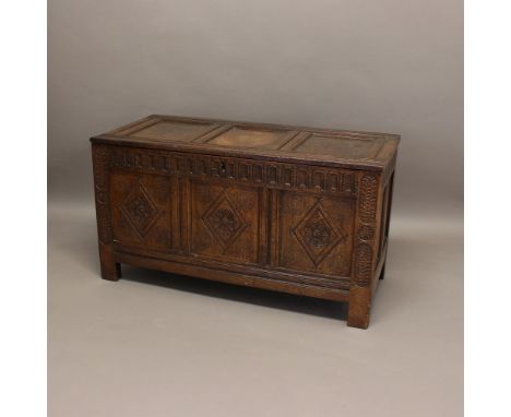 A 17TH CENTURY OAK COFFER. with front with carved floral and diamond panelling, the sides and back also panelled, the interio
