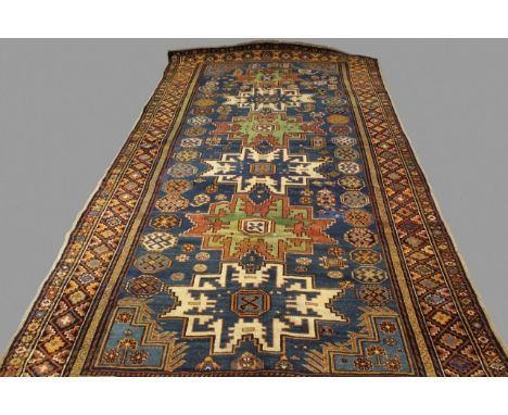 A CAUCASIAN LESGHI RUG, CIRCA 1910. the indigo field with a column of typical stellar devices framed by borders of stepped me