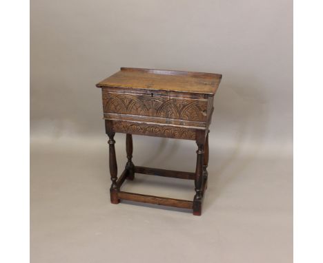 A 17TH CENTURY CARVED OAK BIBLE BOX. with a half hinged top and foliate lunette carving, on a later stand, total height 77cm,