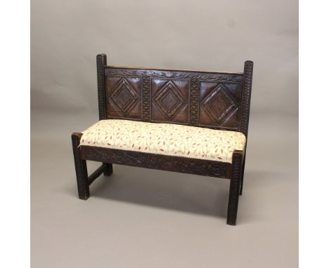 AN OAK HALL BENCH. 18th century and later, the panelled back carved with diamonds, leaves and other geometric devices above a