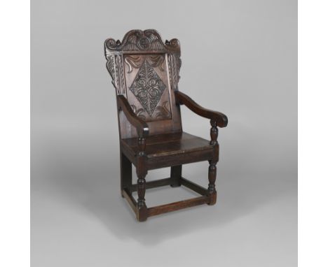 AN OAK WAINSCOT CHAIR. 17th century and later, the scrolling carved top rail above a diamond carved back, downswept arms and 