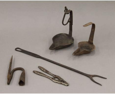 A quantity of old cast/wrought iron kitchenalia to include butter lamps, toasting fork, etc. The largest 44.5 cm long.