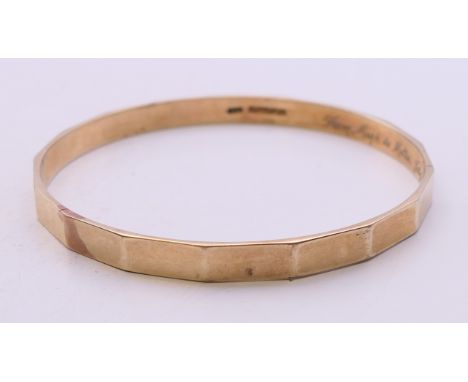 A 9 ct gold bangle with a metal core, inscribed to the interior band 'From Mark to Mollie, July 2nd 1924'. 6.5 cm inner diame
