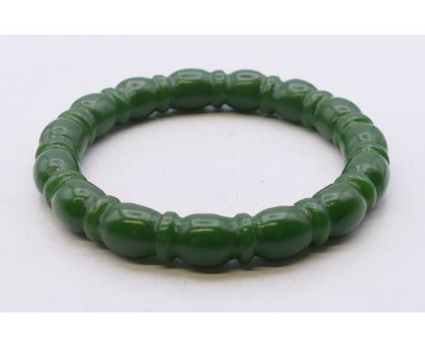A dark green ribbed jade bangle. 6 cm inner diameter.