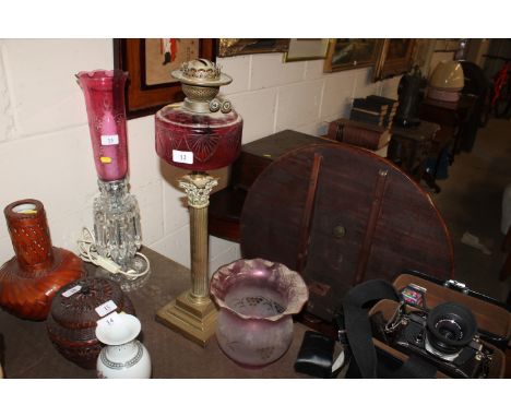 A Victorian Corinthian columned oil lamp with red glass reservoir and an opaque glass shade 