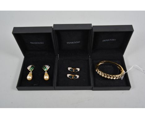 A Swarovski bangle half hinged with black enamel to front and eleven square cut crystals, two pairs of Swarovski earrings, on