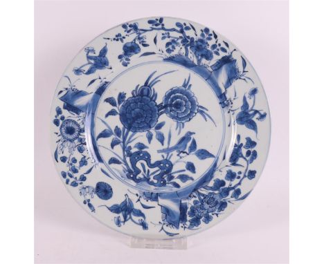 A blue/white porcelain plate, China, Kangxi, around 1700. Blue underglaze floral decor with bird on the shelf, the lip with f