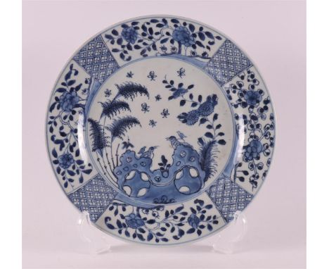 A blue and white porcelain plate, China, Kangxi, 18th century. Blue underglaze decor of birds on a rock and flora, Ø 25 cm.