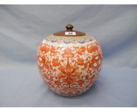 A Chinese bulbous shaped jar with red underglaze scroll decoration with wooden lid, 21 cms high approx.