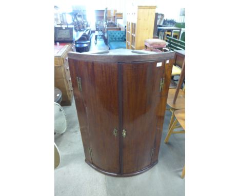 A George III mahogany bow front hanging corner cupboard