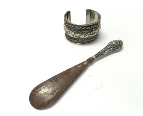 A silver handled Edwardian shoe horn with 1905 Birmingham hallmarks and a white metal, possibly silver, Indian bangle.