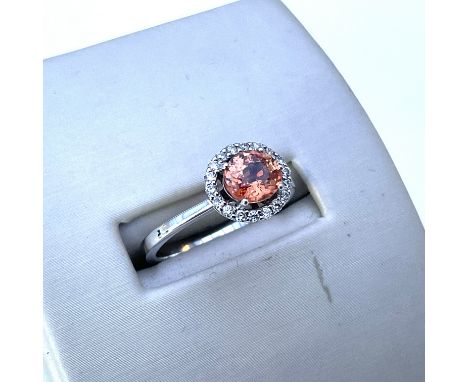 An orange sapphire and diamond halo design ring, O.