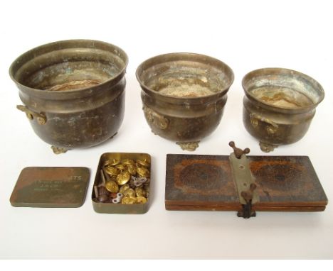 A graduated set of three copper planters, a tie press, regimental buttons, a sunlit cabin shade projector. 