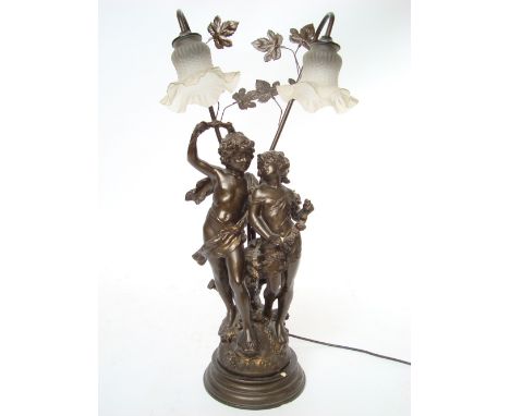 A bronzed resin two light table lamp, cast as two semi clad figures on circular plinth base. 