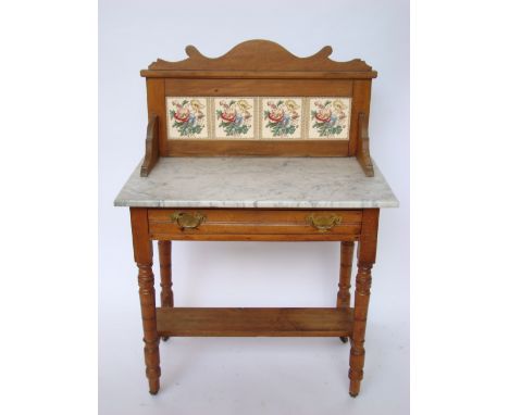 An Edwardian satin walnut washstand, with tiled splashback over a marble top and frieze drawer raised on ring turned legs uni