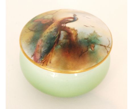 A Royal Worcester pill box and cover, the cover decorated with a hand tinted peacock perched upon a pinecone branch, the base