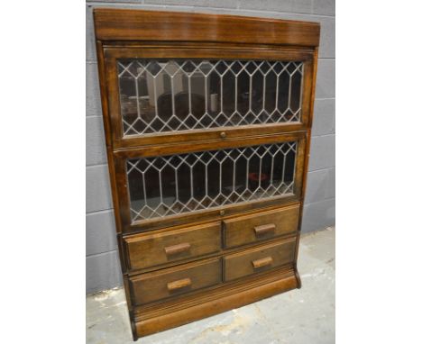 An early 20th Century bookcase in the Globe Wernicke style, enclosed by leaded light doors above drawers and a plinth base, w