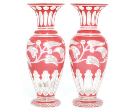 A pair of late 19th Century Bohemian glass vases, each of footed shouldered form with flared neck, cased in pink over opal ov