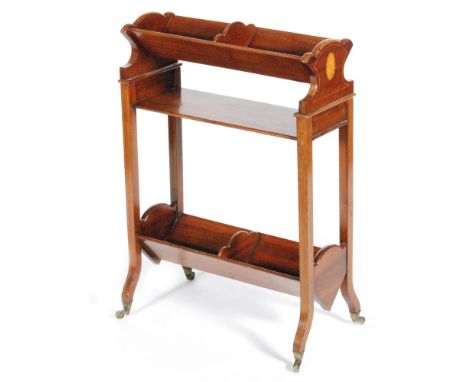 An early 20th Century two tier walnut bookshelf or book trough, with inlaid oval paterae to the sides, raised to brass castor