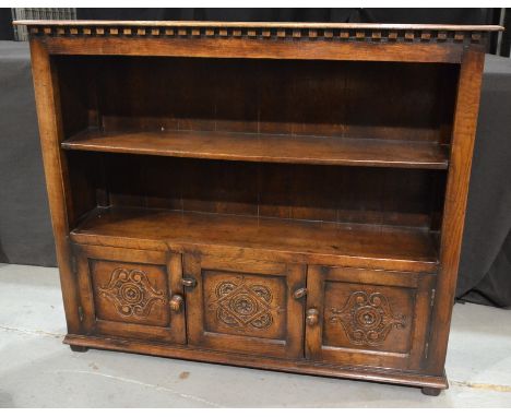 A carved oak open fronted bookcase in the 17th Century style, by C T Rackstraw Ltd Worcester, with a cupboard base, bears mak