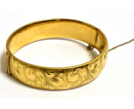 9CT GOLD METAL CORED BANGLE 15.6mm wide bangle, front decorated with scroll and foliate engraving, back plain, hinged to one 