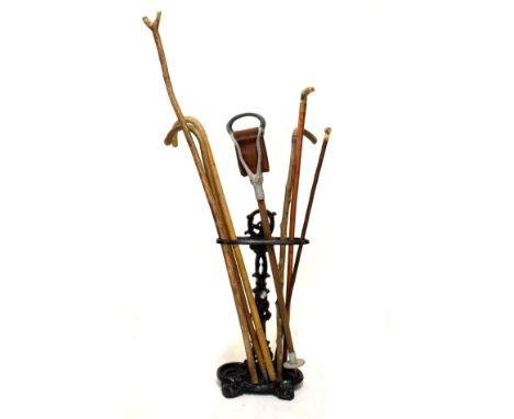 Black painted cast iron stick stand, together with a selection of sticks  