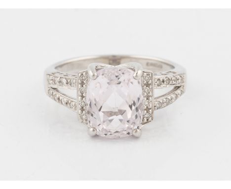 A 9ct white gold kunzite and diamond dress ring, set with a central cushion cut kunzite, measuring approx. 10x8mm, flanked to