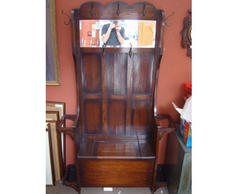 A wooden hallstand with a mirror, coathooks, boxseat and stick stands.