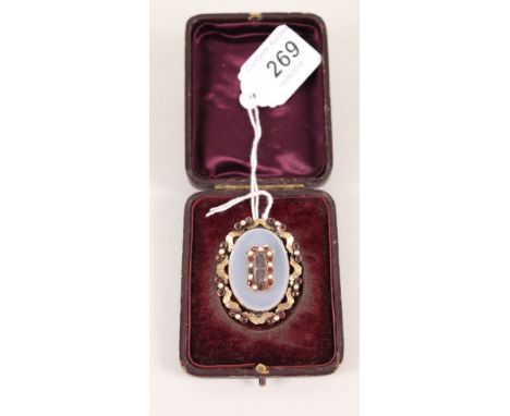 A yellow metal memorial brooch with garnet and pearl decoration and central hair panel under glass