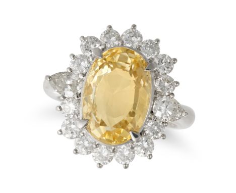 A YELLOW SAPPHIRE AND DIAMOND CLUSTER RING in platinum, set with an oval cut yellow sapphire of 7.92 carats in a cluster of r