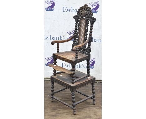 A Charles II style oak and caned child's high chair on stand, 1890s, the ornate pierced cresting with an initialled shield, f