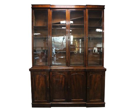A Victorian mahogany bookcase cupboard, circa 1840, of inverted breakfront form, the cornice above four glazed panel doors en