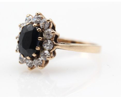 Vintage sapphire cluster ring, set with an oval cut sapphire and twelve round cut cubic zirconia, hallmarked 9 ct 1975, ring 