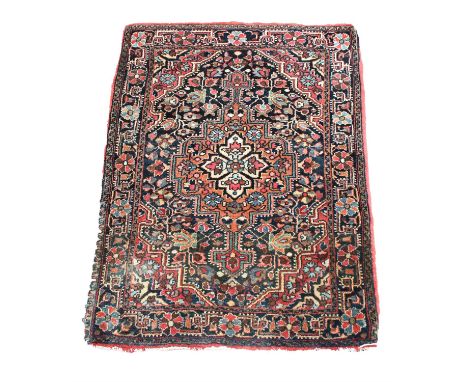 A small Persian mat, with central shaped lozenge, with four petal foliate device, flower strewn and flower head borders, 85 x