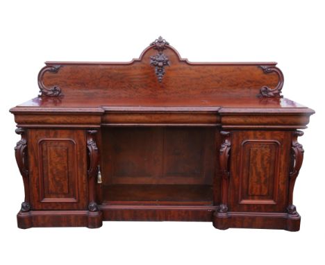 A large Victorian mahogany pedestal sideboard, 1840s, of inverted breakfront form, the arched splashback with a central leaf 