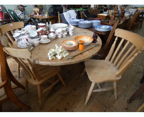 A circular stripped pine single pillar dining table 4' diameter and three farmhouse style slat back Windsor chairs 