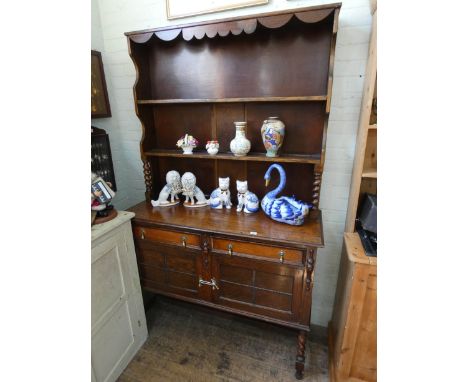 A 1930's oak dresser with shelf back, drawers and cupboards under standing on barley twist legs, 4' wide 