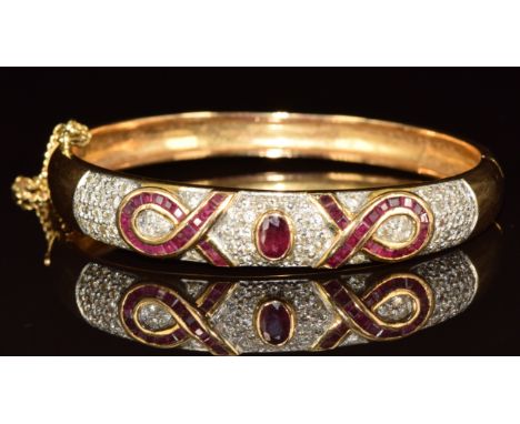 An 18ct gold bangle set with an oval cut ruby of approximately 0.4ct, calibre cut rubies and round cut diamonds, 32g, 5.5 x 5