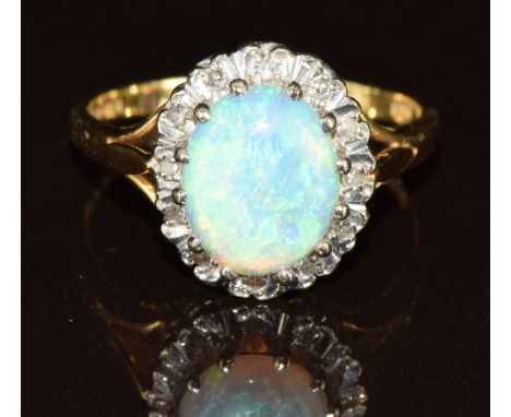 An 18ct gold ring set with an oval cut opal cabochon surrounded by diamonds, 4.5g, size O