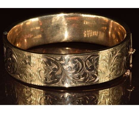 A 9ct gold bangle with engraved scrolling decoration, 27.2g, 6.5 x 5.8cm