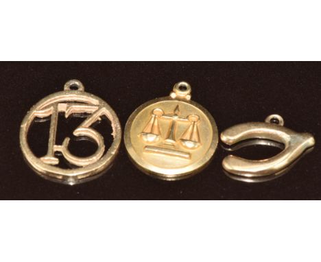 Four 9ct gold charms including wishbone, bell, '13', and Libra scales, 5.4g