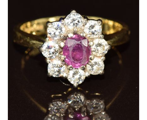 An 18ct gold ring set with an oval cut ruby of approximately 0.6ct surrounded by eight diamonds, the total diamond weight app