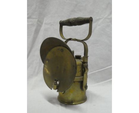 An old brass mounted acetylene miners lamp by the Premier Lamp Co. Leeds with circular reflector and turned wood handle