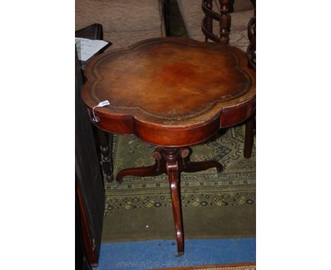 A reproduction floriate shaped Mahogany finished drum Table, having inset brown leather top, standing on turned pediment base