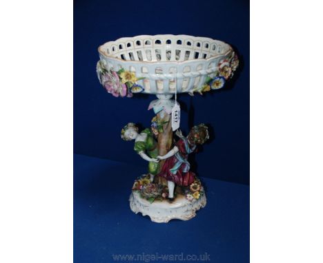 A Continental china Centrepiece with encrusted flowers to the exterior of the dish and two figures of young Girls playing aro
