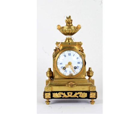 19th Century French gilt brass mantel clock, the flame urn finial top above a stepped case and stile feet, the white enamel d