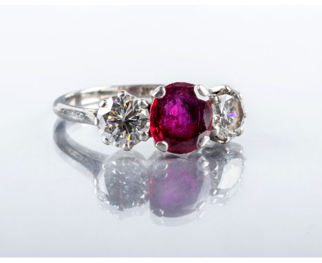 A THREE STONE RUBY AND DIAMOND RING, the circular facet cut ruby claw set and flanked by two brilliant cut diamonds each of a