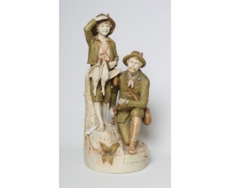 A ROYAL DUX FIGURE GROUP, early 20th century, the hunter kneeling and holding a rifle, his young barefoot son at his side car