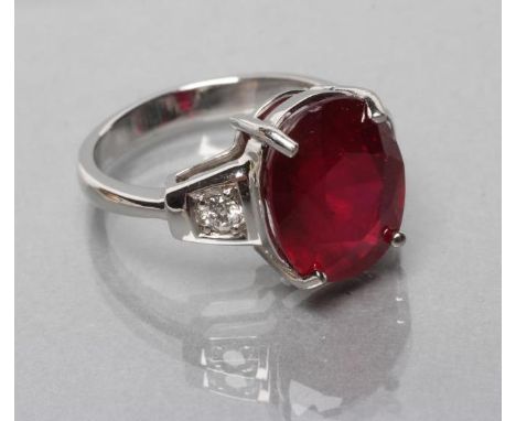 A RUBY RING, the oval facet cut stone of approximately 7.7cts, claw set to shaped shoulders each set with a brilliant cut dia