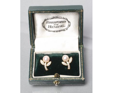 A PAIR OF CULTURED PEARL AND DIAMOND EAR STUDS, the pearl flowerheads with diamond set leaves and stalk, to 18ct gold mounts,